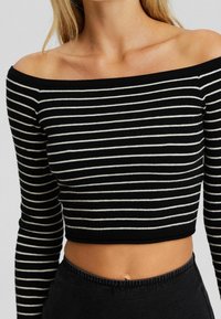 Czarna i biała w paski crop top bez ramiączek z długimi rękawami, prążkowana tekstura i dopasowany krój.