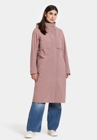 Lång rosa kappa med hög krage och huva. Tillverkad av ett slätt tyg, med en framficka och avslappnade, vida ärmar.