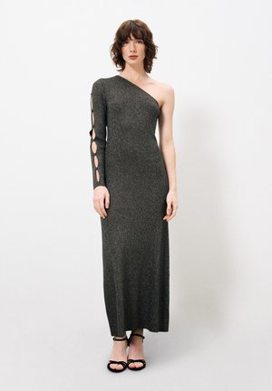 Robe longue, ajustée, à une épaule en gris foncé avec un effet scintillant. Présente des détails découpés sur le bras gauche et une jupe unie.