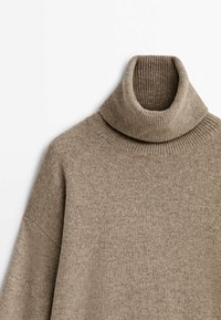 Beżowy sweter z golfem, pleciony, z prążkowanym kołnierzem i bezszwowym wykończeniem ramion, wyeksponowany na jednolitym białym tle.