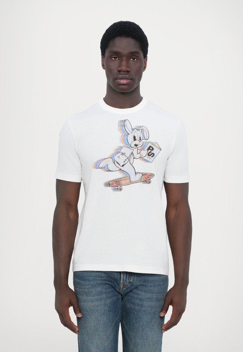 T-shirt en coton blanc avec un design de lapin cartoon coloré, faisant du skateboard, avec des accents bleus et un graphique montrant "PS" dans une boîte.