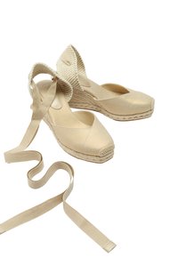 Beżowe espadryle z teksturowaną cholewką, plecioną podeszwą z liny i długimi sznurkami z materiału. Mają okrągły czubek i odkryty tył.