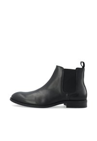 Botín Chelsea de cuero negro con paneles elásticos en los lados, punta redondeada y tacón bajo apilado. Textura suave y diseño minimalista.