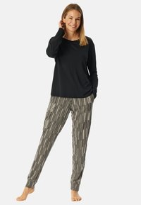 Zwarte langemouwen top gecombineerd met gestreepte pyjamabroek in grijs en wit. De broek heeft verticale strepen en elastische boorden.