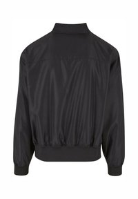 Veste noire en tissu lisse et brillant. Présente un col, un ourlet élastique et des poignets élastiques, avec un design simple sans motifs visibles.