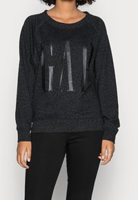 Sweat-shirt noir avec un motif léopard, arborant un graphique "GAL" brillant sur le devant, col rond et manches longues.