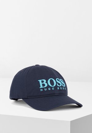 Granatowa czapka z daszkiem typu baseball z zakrzywionym daszkiem, z jasno niebieskim haftowanym logo „BOSS HUGO BOSS” z przodu, prezentowana na białej powierzchni.