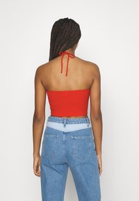 Top corto a coste rosso con collo all'americana alla moda, abbinato a jeans in denim blu a vita alta con pannelli azzurri.