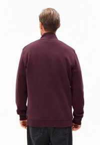 Bordeaux sweatshirt met een hoge kraag, lange mouwen en geribbelde manchetten. Glad textuur en casual ontwerp. Draagt met donkere jeans.