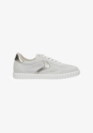 White perforated sneaker with white laces, a thick ridged sole, and metallic silver accents on the heel and sides.