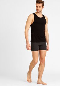 Schwarzes Tanktop und dunkelgraue Boxershorts. Das Tanktop hat ein einfaches Design mit breiten Trägern und besteht aus einem glatten, elastischen Stoff.