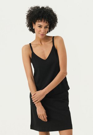 Top in satin nero con spalline sottili e scollatura a V, abbinato a una gonna nera aderente, realizzata in tessuto liscio, su uno sfondo chiaro.