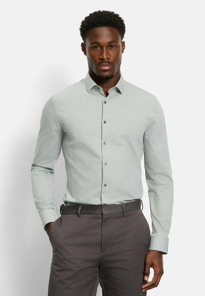 Light green button-up shirt with a small-scale textured pattern, long sleeves, and a standard collar, paired with dark gray pants.