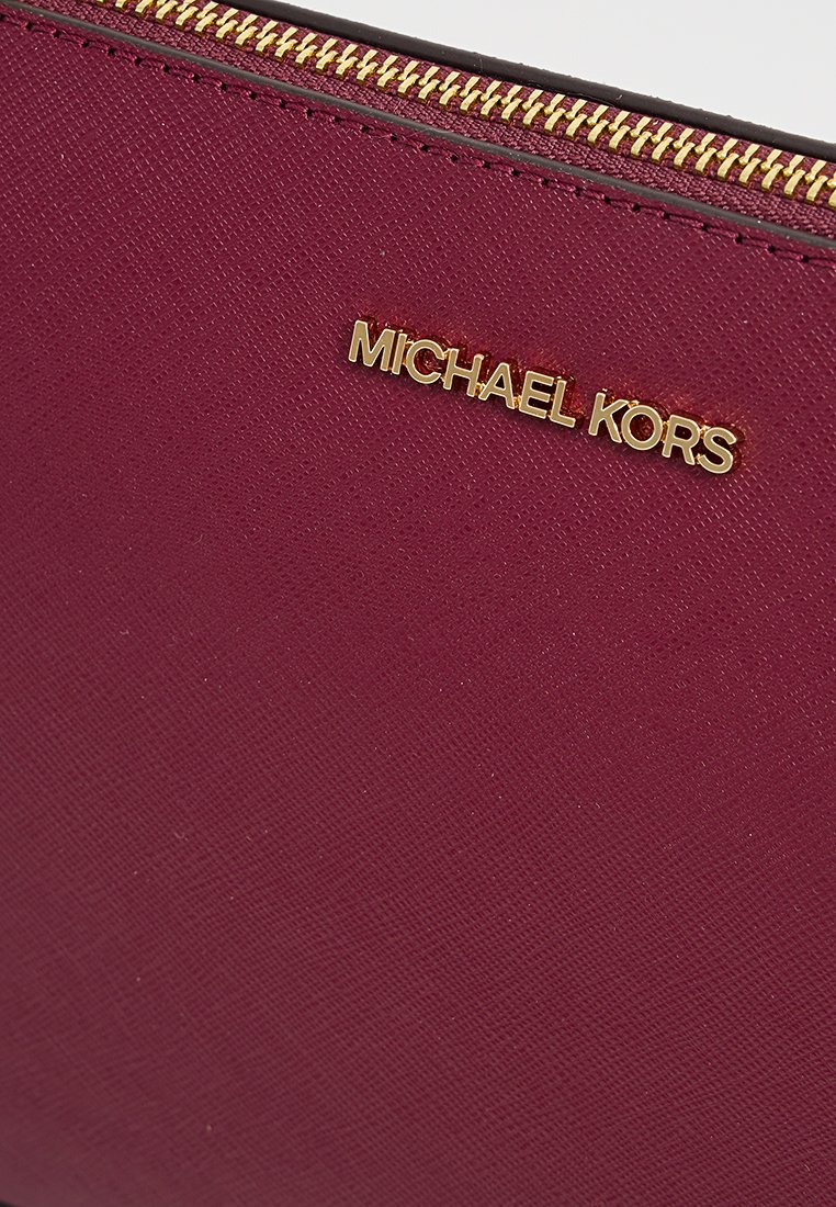 Borsetta testurizzata color bordeaux con zip dorata, caratterizzata da un logo "MICHAEL KORS" dorato ben visibile sul davanti.