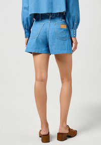 Ljusblå denimshorts med en avslappnad passform, med bakfickor och en liten varumärkesetikett. I kombination med bruna klacksandaler med blockklack.