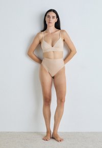 Naha kahe tükkidega ujumiskostüüm, millel on V-kaelusega bralette'i ülemine osa ja kõrge vöökohaga alumine osa; valmistatud siledast ja venivast kangast.