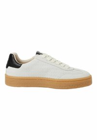 Hvit teksturert sneaker med kremfargede lisser, svart skinnheelskinn og lys brun gummisåle med mønsterdesign.