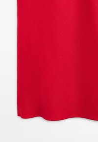 Rood stoffen paneel met een gladde textuur, licht gebogen zoom, gefotografeerd tegen een witte achtergrond.