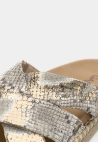 Sandale à enfiler à imprimé serpent avec brides croisées en nuances de gris et beige, dotée d'une semelle tissée de couleur naturelle et d'une finition texturée.