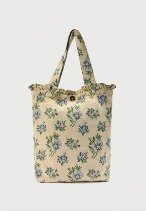 Beige fabric tote bag with ruffled top edge, button closure, and blue floral pattern with green leaves.