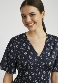 Robe imprimée florale marine avec des manches courtes, un col en V et des boutons sur le devant. Le matériau semble léger avec une texture douce.