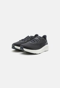 Schwarze Sportschuhe mit einem strukturierten Obermaterial, einer kontrastierenden weißen Zwischensohle und grauen Akzenten an der Seite, mit einem Schnürverschluss.