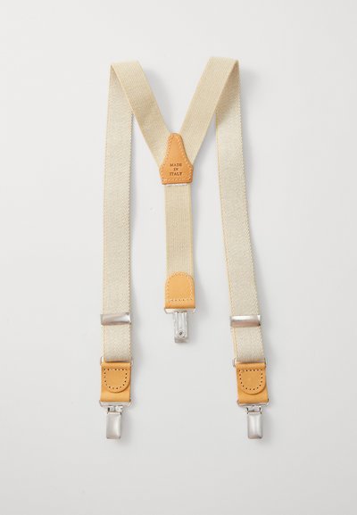 Beige šle s koženými detaily a stříbrnými sponami. Tkanina je texturovaná, uprostřed je nášivka s nápisem "MADE IN ITALY."