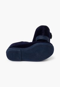 Zapatos de terciopelo azul marino con una suela de goma sólida que presenta patrones de agarre texturizados. Punta redondeada y acento decorativo de hebilla en el lado.