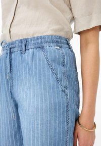 Pantaloni in denim a righe blu chiaro con vita elastica, cordoncino e tasche laterali, caratterizzati da una vestibilità comoda e dettagli di cucitura sottili.
