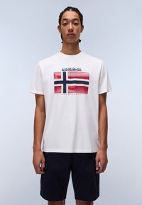 Camiseta de algodón blanca con un gráfico frontal de la bandera noruega en rojo, blanco y azul, con el texto "NAPAPIJRI geographic" arriba.