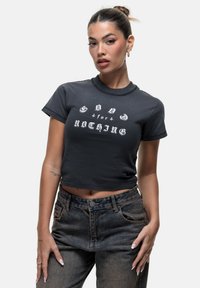 T-shirt noir court en coton doux avec un col rond et un texte graphique blanc "GOOD for NOTHING" dans des styles de police contrastés.