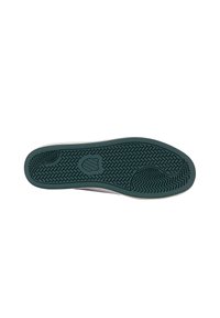 Talpa unei încălțări cu o suprafață din cauciuc texturat de culoare verde închis, având un model în zig-zag și un logo circular în centru.