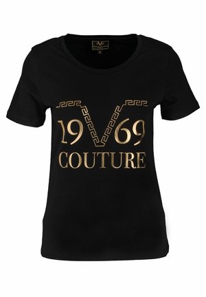 T-shirt noir à manches courtes avec texte doré "1969 COUTURE" et un motif décoratif en V au centre devant.