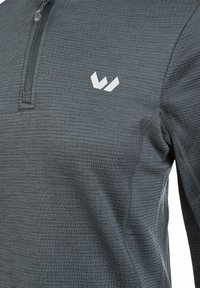 Graues, langärmliges Sportoberteil aus strukturiertem Stoff. Mit einem teilweisen Reißverschluss und einem kleinen weißen Logo auf der Brust.