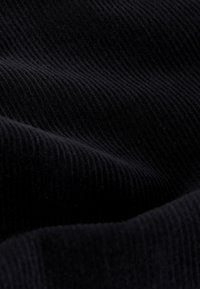 Schwarzer Cordstoff mit sichtbarer gerippter Textur, glatter Oberfläche und weichem Aussehen, geeignet für verschiedene Kleidungsstücke.