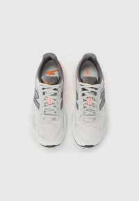 Ein Paar hellgraue sportliche Laufschuhe mit weißen Schnürsenkeln, dunkelgrauem Innenfutter und orangefarbenen Logoakzenten, von oben betrachtet.