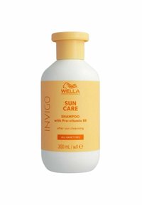Valkoinen pullo keltaisella korkilla, jossa on oranssia tekstiä. Etiketissä lukee "Wella Professionals Invigo Sun Care Shampoo", 300 ml, sopii kaikille hiustyypeille.
