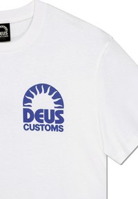 Camiseta de algodón blanca con un logotipo gráfico azul que presenta un motivo solar y el texto "DEUS CUSTOMS", de manga corta y cuello redondo.