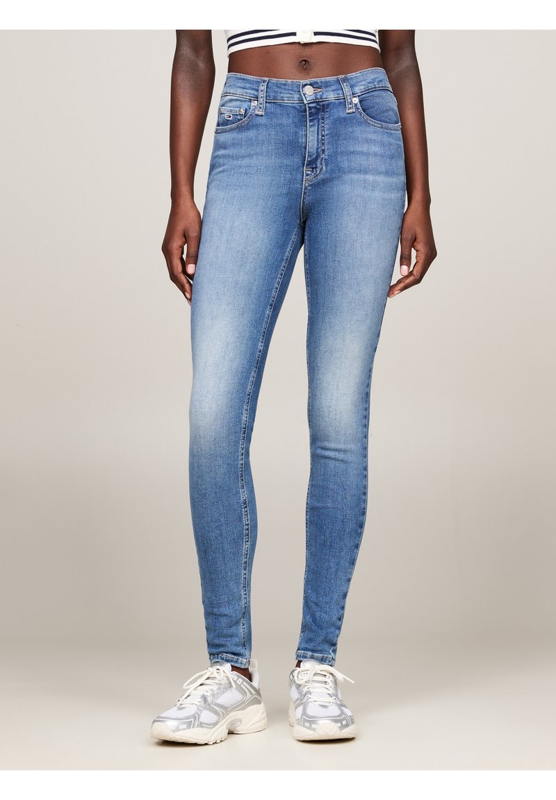 Hoikkan siniset farkut korkealla vyötäröllä, joissa on haalistumismalli, viisi taskua ja hopeavälineet. Konepesun kestävä kangas.