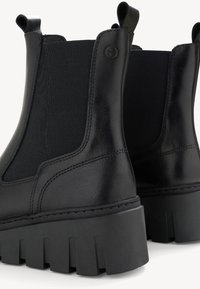 Schwarze Leder-Chelsea-Stiefel mit elastischen Seitenpaneelen, einer strukturierten Oberfläche und einer dicken, robusten Gummisohle mit tiefen Rillen.