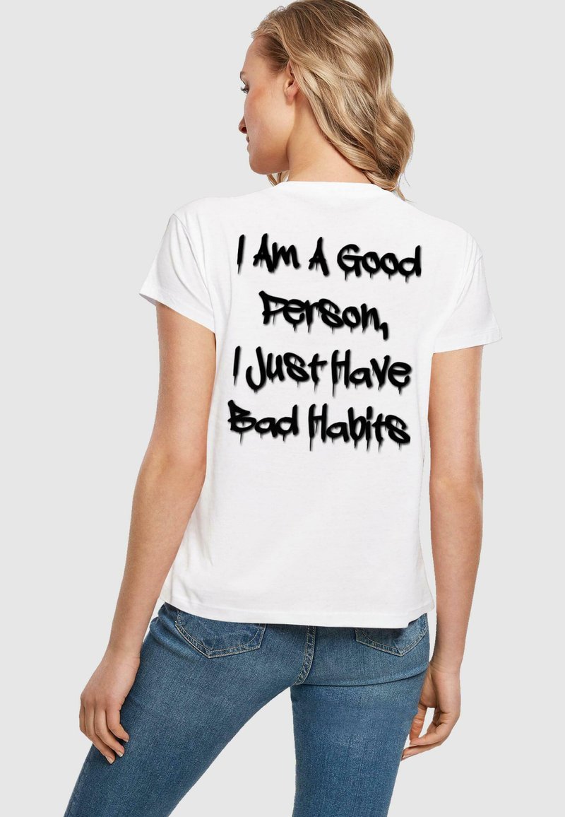 Hvid bomulds T-shirt med en afslappet pasform, der har sort graffiti-agtig tekst på ryggen, som siger: "Jeg er en god person, jeg har bare dårlige vaner."