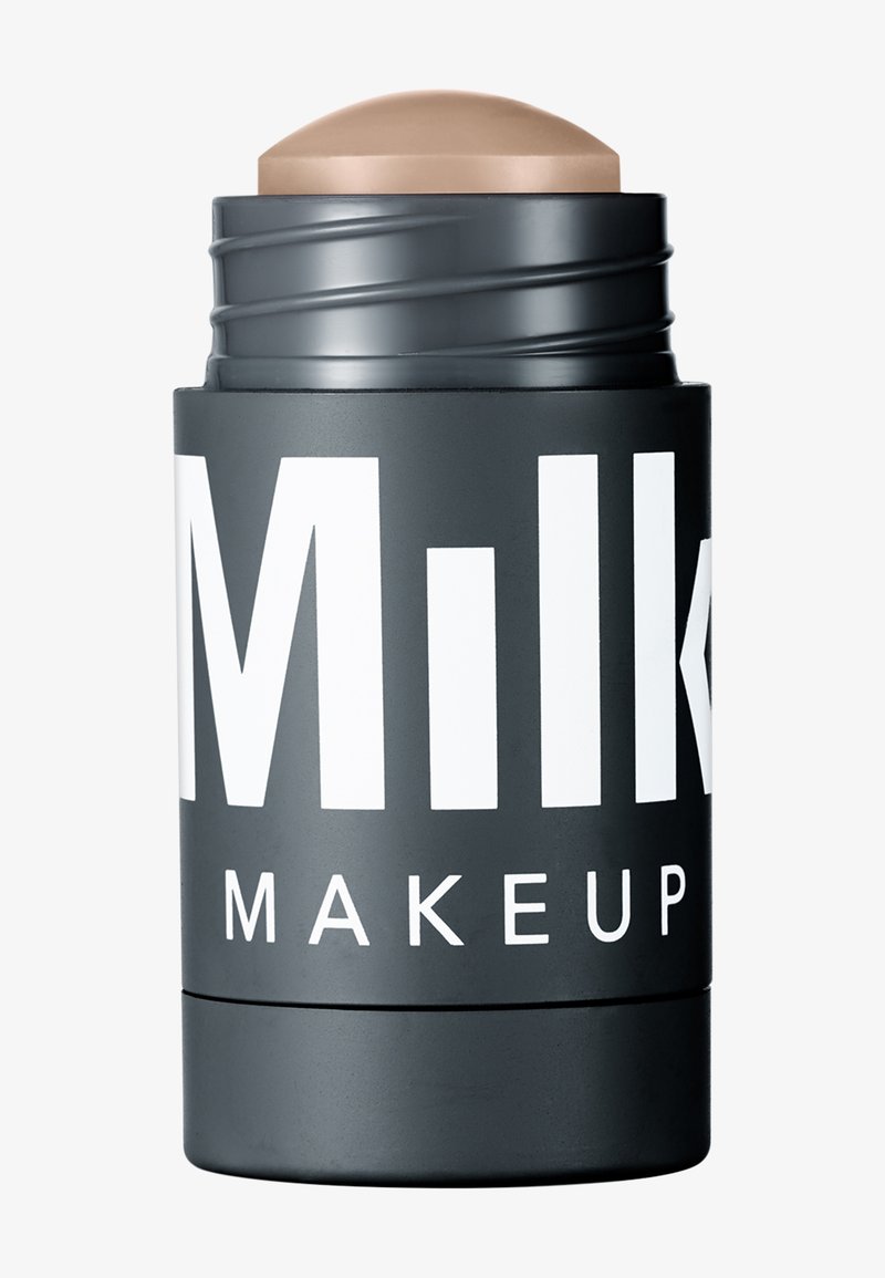 Black cylindrical container with large white text, topped with a beige, rounded stick. Smooth matte finish, compact size for makeup application.
