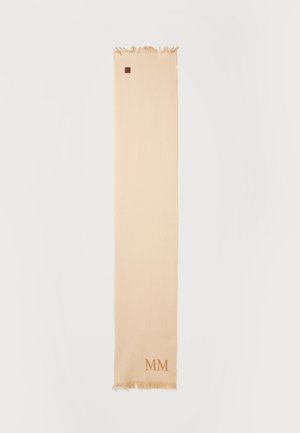Longue écharpe beige avec extrémités à franges et petits lettrages bruns "MM" près d'une frange, posée à plat sur un fond blanc.