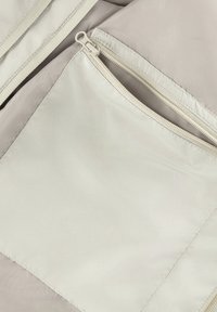 Bežinė medžiaginė dėžutė su užtrauktuku. Medžiaga lygi, su subtiliu blizgesiu. Stačiakampio formos su švariais kraštais ir sustiprinta siūlėmis.