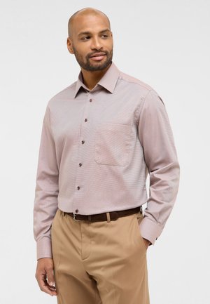 Camicia button-up rosa chiaro con un discreto motivo a spina di pesce, taschino sul petto, bottoni marroni e maniche lunghe, abbinata a pantaloni beige.