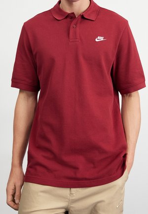 Bordowa koszulka polo z kołnierzykiem. Wykonana z teksturowanej tkaniny, z małym białym logo Nike po lewej stronie klatki piersiowej.