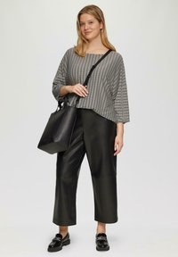 Zwart gestreepte blouse met een wijde halslijn, gecombineerd met zwarte leren cropped broeken. Een zwarte tote bag met stevige handvatten en glanzende loafers.