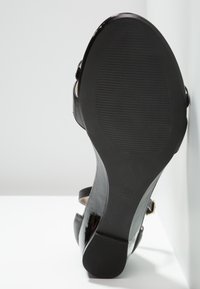 Sandale à talons noire pour femmes montrant la semelle texturée et la pointure 37 sur fond blanc.