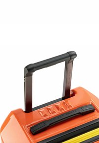 Maleta naranja brillante con un asa retráctil negra, acentos negros texturizados y una cremallera visible en un amarillo contrastante. Logo en el asa.