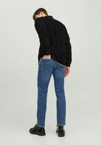 Must mustrits, sinised denim teksad, slim fit, tagavaade, mustad seotud saapad, n�äidates minimaalset detaili taskutel.